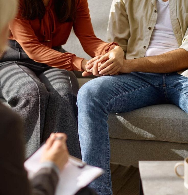 A couple sitting close together, engaged in a supportive conversation.